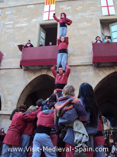 Castellers form a traditional Catalonian human Castle in front of Manresa town hall while the king and royal family look on from the balcony .These towers are typical across Catalonia and are often bigger than the one shown here.