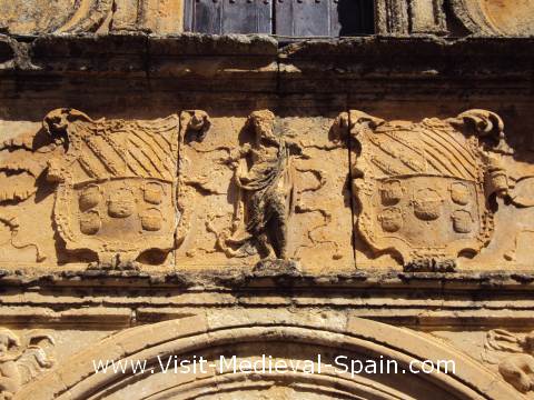 Heavily weathered medieval stone carvings above a doorway, Spain