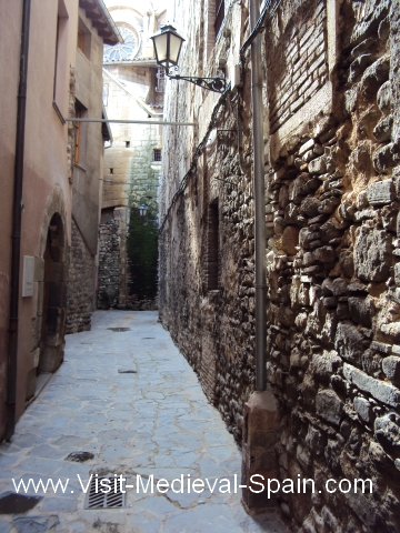 A narrow street scene showing the medieval cathedral and hospital of Vic