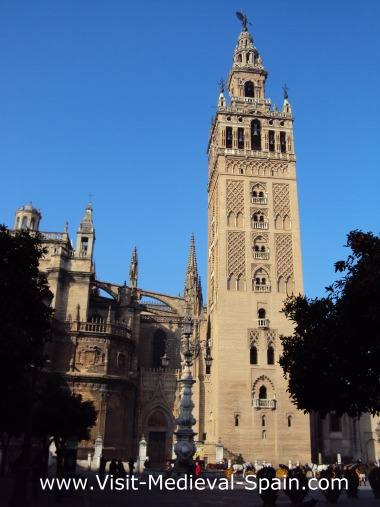 The medieval Cathedral and La Giralda tower in Seville Spain, photo taken on a sunny day with orange trees siuluetted in the forground