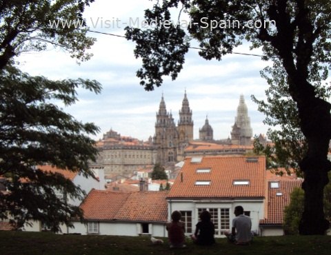 The Medieval Cathedral od Santiago de Compostela, view from the Alameda park with people and trees silueted in the foreground