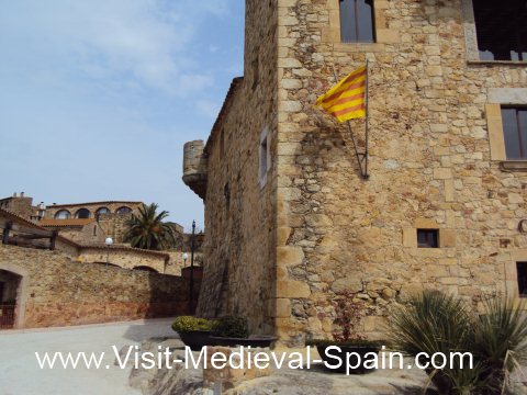 A Catalan flag flying on the side of a medieval stone house in Pals near Girona, Spain