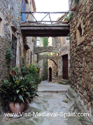 Narrow Street with a bridge and arches between stone houses in the medieval village of Pals, Catalonia.